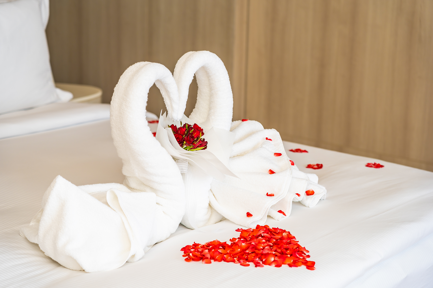 swan towel on the bed with red rose flower petals